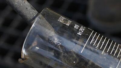 An employee at the Oelweg oil company takes a sample of oil from an oil well in Oberlauterbach. Vincent Kessler / Reuters