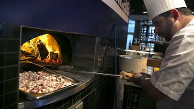 Justin Galea, Executive Chef and Director of Food & Beverage at the Le Royal Meridien hotel in Abu Dhabi, puts food into a wood oven at the #healthyliving cooking experience. Silvia Razgova / The National