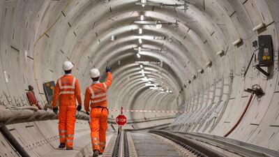 FILE - In this Sept. 14, 2017 file photo, Crossrail engineers walking alongside completed tracks. London's new east-west railway, Crossrail, says it will miss its scheduled December opening by almost a year, with passenger services not starting until late 2019. (Dominic Lipinski/PA via AP)