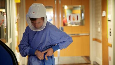 Nurse Alex Krajek puts on PPE as he prepares to enter a patient room in a wing housing Covid-19 patients at UW Health University Hospital in Madison, Wisconsin. Reuters