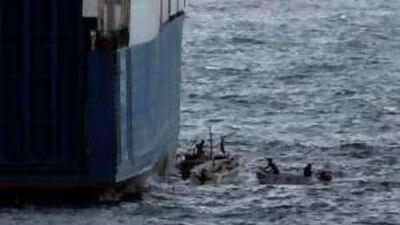 Somali pirates in small boats are seen alongside the hijacked Faina.