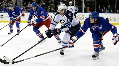 Winnipeg's Andrew Lad battles New York Rangers' Marc Staal for the puck.
