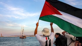 A man waves a Palestinian flag to other activists riding aboard a vessel departing from Bizerte in Tunisia. AFP