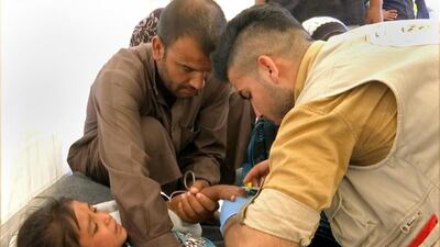 A man comforts his daughter as a doctor treats her after she was taken ill with suspected food poisoning in the Hassan Sham U2 camp for displaced people located about 20km east of Mosul, Iraq on June 13, 2017. Iraq's health minister, Adila Hamoud, said 752 people had been taken ill and at least two died after they took part in a Monday night iftar meal. Balint Szlanko/AP Photo